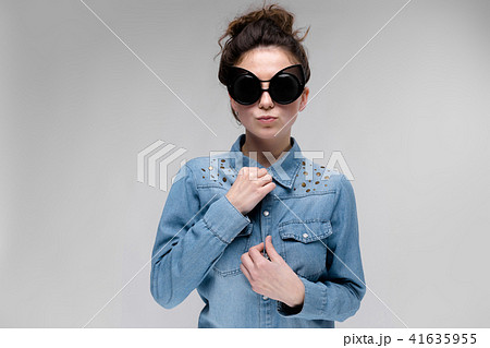 Young brunette girl in black glasses. Cat glasses. The hair is gathered in a bun. The girl adjusts 41635955