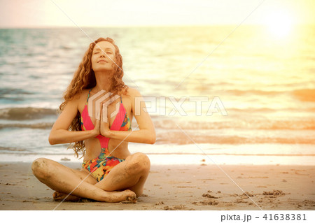 Young woman practices yoga on the beach in summer. Young woman practices yoga on the beach in summer. 41638381