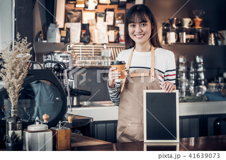 Asian female barista holding coffee and blackboard Asian female barista holding coffee and blackboard 41639073