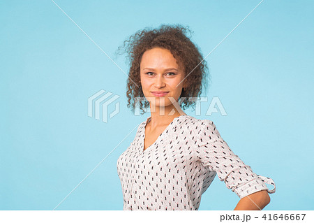 Mixed race female with Afro hairstyle wearing casual shirt over blue background. Beautiful woman 41646667