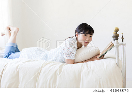 ベッドに寝そべって本を読む若い女性 ベッドに寝そべって本を読む若い女性 41648376