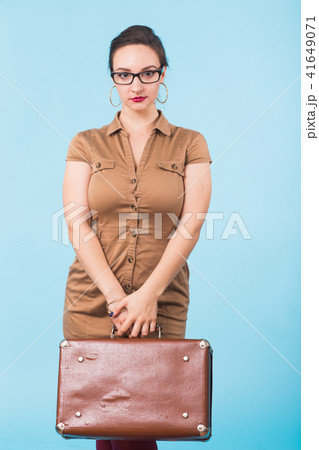 Portrait of excited young woman holding a suitcase isolated over blue background, Travel, holidays Portrait of excited young woman holding a suitcase isolated over blue background, Travel, holidays 41649071