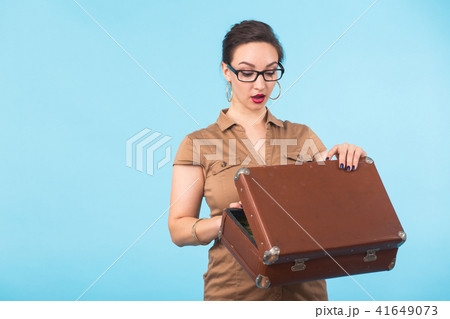 Portrait of excited young woman holding a suitcase isolated over blue background, Travel, holidays 41649073