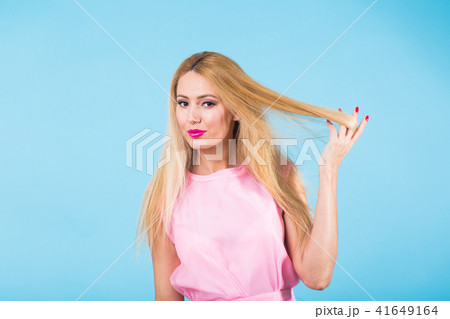 Beautiful woman with long straight blond hair. Fashion model posing at studio on blue background 41649164