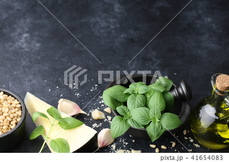Basil leaves, parmesan cheese and other pesto sauce ingredients on black 41654083