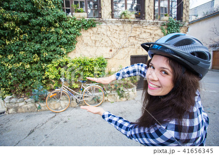 Young woman with helmet posing on bicycle and alley background Young woman with helmet posing on bicycle and alley background 41656345
