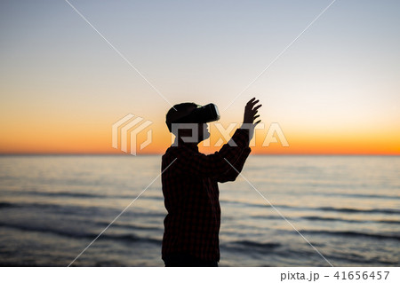 Man using virtual reality glasses on over beautiful sky and sea background 41656457