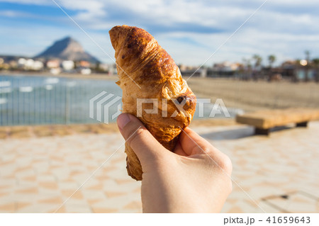 Croissant in hand against the backdrop of a beautiful beach 41659643