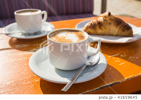 Two cups of invigorating cappuccino and a croissant for breakfast 41659645