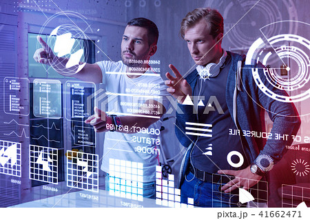 Careful programmer touching the screen and his colleague looking at it Careful programmer touching the screen and his colleague looking at it 41662471