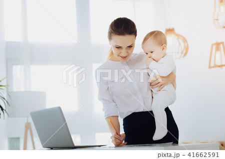 Attentive businesswoman working with her child Attentive businesswoman working with her child 41662591