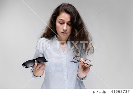 Young brunette girl with glasses. The girl is holding two pairs of glasses. 41662737