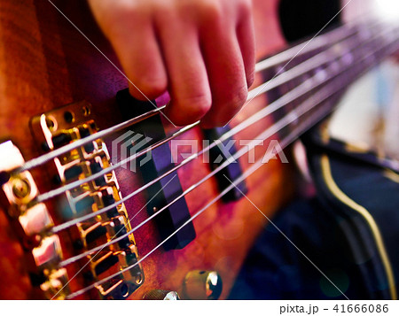 Hand playing bass guitar during a performance. Hand playing bass guitar during a performance. 41666086