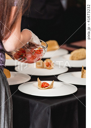 Hand of a girl puts tomato in tacos. The chef at the restaurant is going to make Spicy Shrimp Tacos 41673232