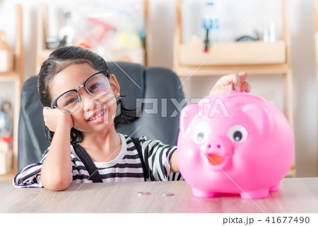 Asian little girl in putting coin in to piggy bank Asian little girl in putting coin in to piggy bank 41677490