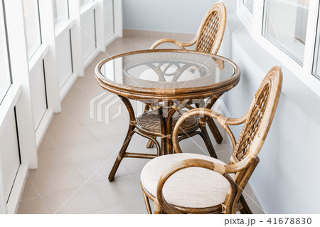 glass table and rattan wicker seat chair. Wicker furniture rattan table two chairs near the window 41678830