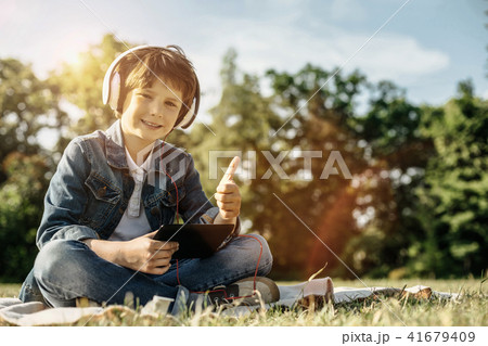 Smiling boy with tablet and headphones showing thumb up 41679409