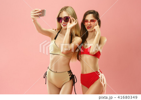 Cute girls in swimsuits posing at studio. Summer portrait caucasian teenagers on pink background. Cute girls in swimsuits posing at studio. Summer portrait caucasian teenagers on pink background. 41680349