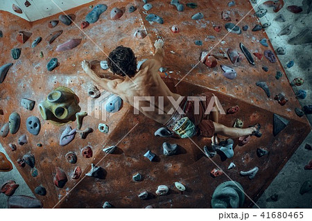 Free climber young man climbing artificial boulder indoors Free climber young man climbing artificial boulder indoors 41680465