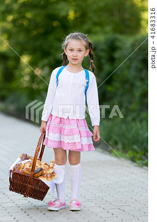 A child with a basket of bread is on the road. A child with a basket of bread is on the road. 41683316