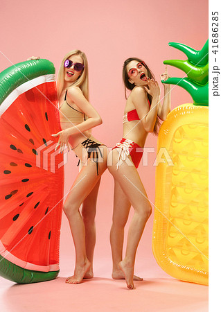 Cute girls in swimsuits posing at studio. Summer portrait caucasian teenagers on pink background. Cute girls in swimsuits posing at studio. Summer portrait caucasian teenagers on pink background. 41686285