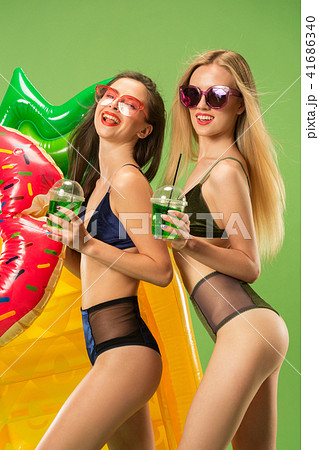 Cute girls in swimsuits posing at studio. Summer portrait caucasian teenagers on green background. Cute girls in swimsuits posing at studio. Summer portrait caucasian teenagers on green background. 41686340
