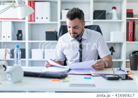 A man is sitting in the office and working with documents. 41690817