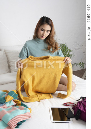 Woman packing her clothes for journey on bed. Woman packing her clothes for journey on bed. 41694410