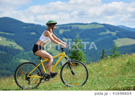 Young happy woman riding bicycle in the mountains at summer day Young happy woman riding bicycle in the mountains at summer day 41696604