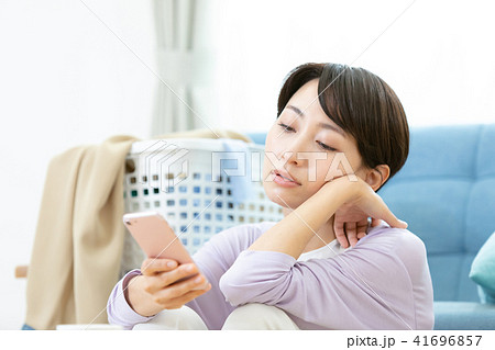 スマホを使う女性　女性ポートレイト　笑顔　白い家　おしゃれな家　白い背景と女性のタグ 41696857