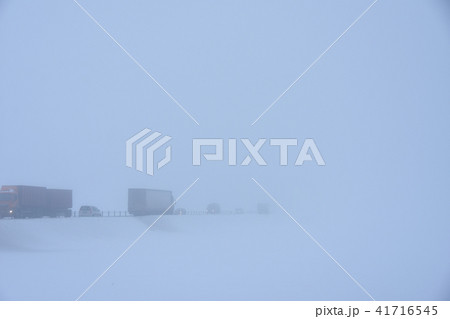 Cars drive on a winter snowy road in dense fog Cars drive on a winter snowy road in dense fog 41716545