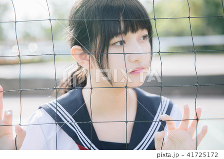 Portrait of beautiful Asian japanese high school girl uniform looking with net in green background 41725172