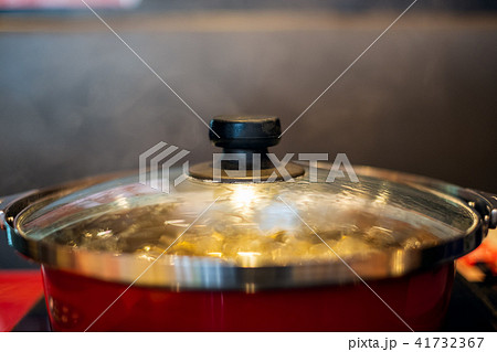 Boiling soup in red pot with smoke on table Boiling soup in red pot with smoke on table 41732367