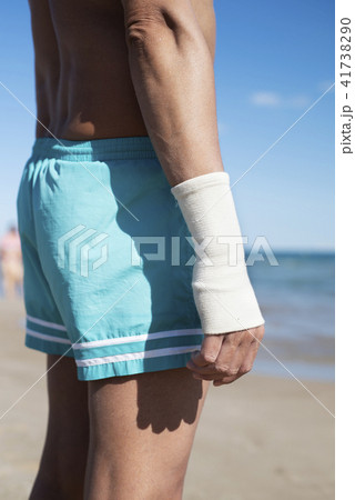 man on the beach with a bandage in his wrist 41738290