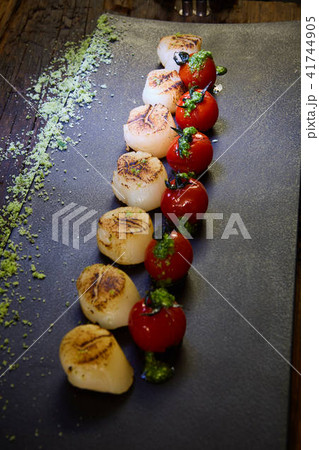 Fried scallops with tomatoes on a black plate. Shallow dof. 41744905