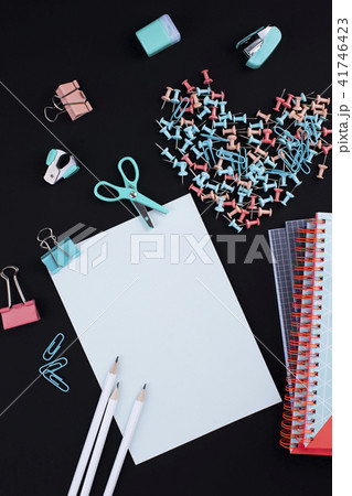 Many multi-colored paper clips and paper on a black background. Office concept. Subjects for the 41746423