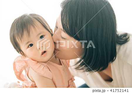 赤ちゃんの頬にキスする若い母親の写真素材