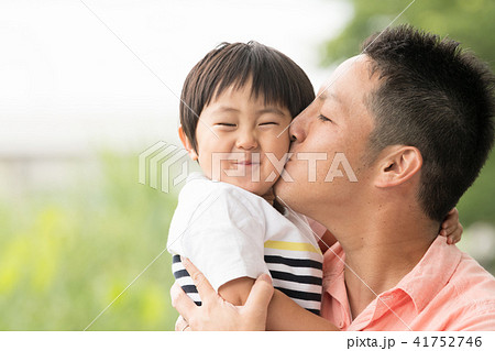 息子の頬にキスする若い父親 の写真素材