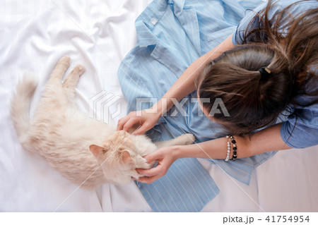 Girl and red fluffy cat lying on bed with pajamas Girl and red fluffy cat lying on bed with pajamas 41754954
