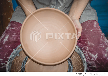 Potter holds round clay plate in his hands. Potter holds round clay plate in his hands. 41763582