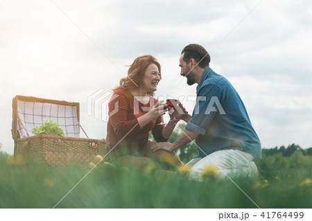 Joyful husband and wife drinking wine on meadow Joyful husband and wife drinking wine on meadow 41764499