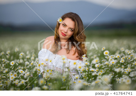 Beautiful woman on the camomile field is wearing white dress, spring time Beautiful woman on the camomile field is wearing white dress, spring time 41764741
