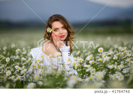 Beautiful woman on the camomile field is wearing white dress, spring time Beautiful woman on the camomile field is wearing white dress, spring time 41764748