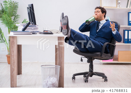 Young businessman employee drinking in the office at desk Young businessman employee drinking in the office at desk 41768831