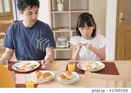 小学生の女の子と父親の朝食風景の写真素材