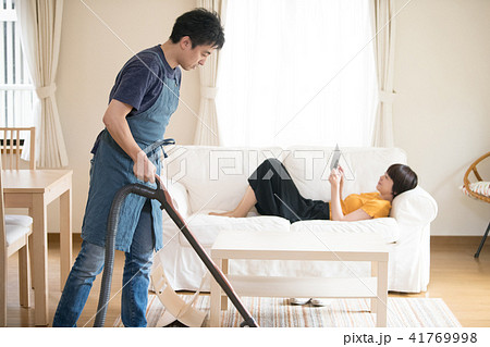 掃除をする夫とソファでくつろぐ妻 41769998