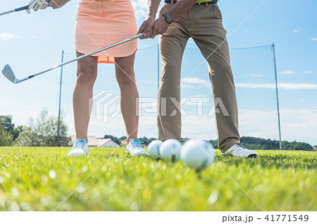 Low section of man and woman holding iron clubs while practicing 41771549