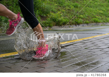 Single runner running in rain and making splash in puddle 41780268