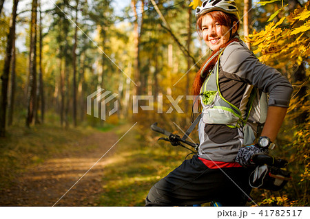 Photo of girl in helmet on bicycle in autumn forest 41782517
