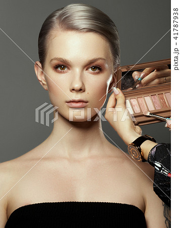 Beautiful girl surrounded by hands of makeup Beautiful girl surrounded by hands of makeup 41787938